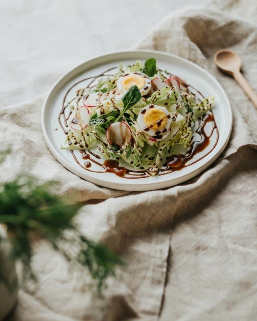 Green salad with egg and radish, finished with dark pumpkin seed oil